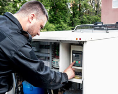 HVAC technician servicing the electrical panel of an outdoor air conditioner unit in Durham Region