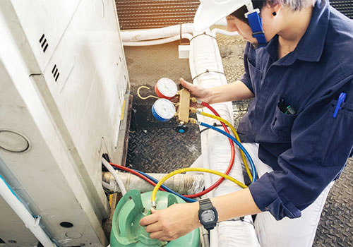 HVAC technician using manifold gauges to service a home heating system — gas vs electric furnace guide, Ontario