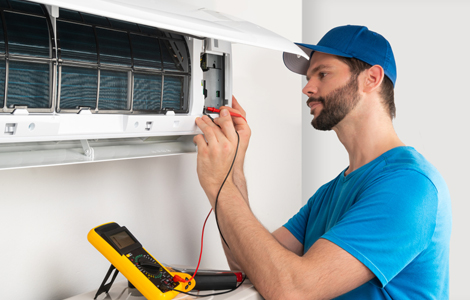 Air conditioner service frequency in Durham: a technician servicing an AC before summer to prevent failures