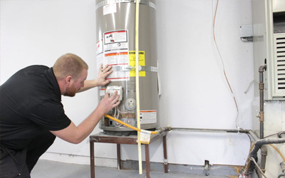 Technician performing water heater maintenance on a residential hot water tank