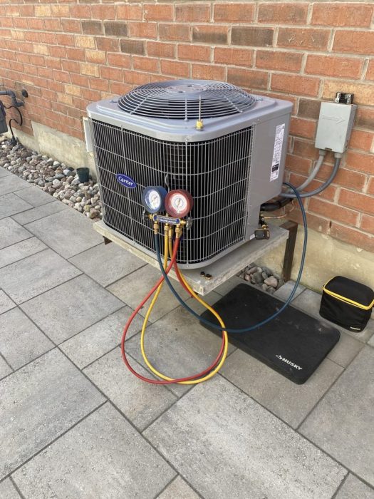 HVAC technician gauges connected to a Carrier air conditioner during commissioning