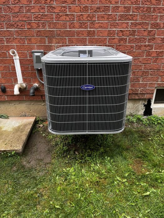 New Carrier central air conditioner installed beside a brick home in Whitby, Ontario