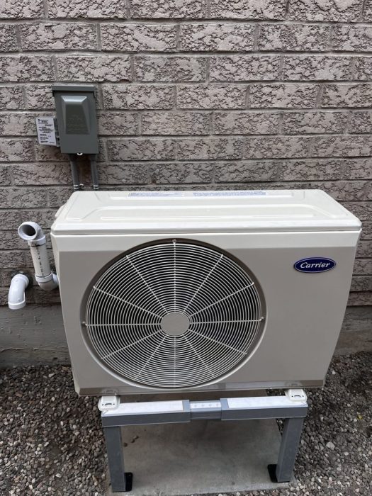 Carrier heat pump outdoor unit installed on a levelled stand beside a home